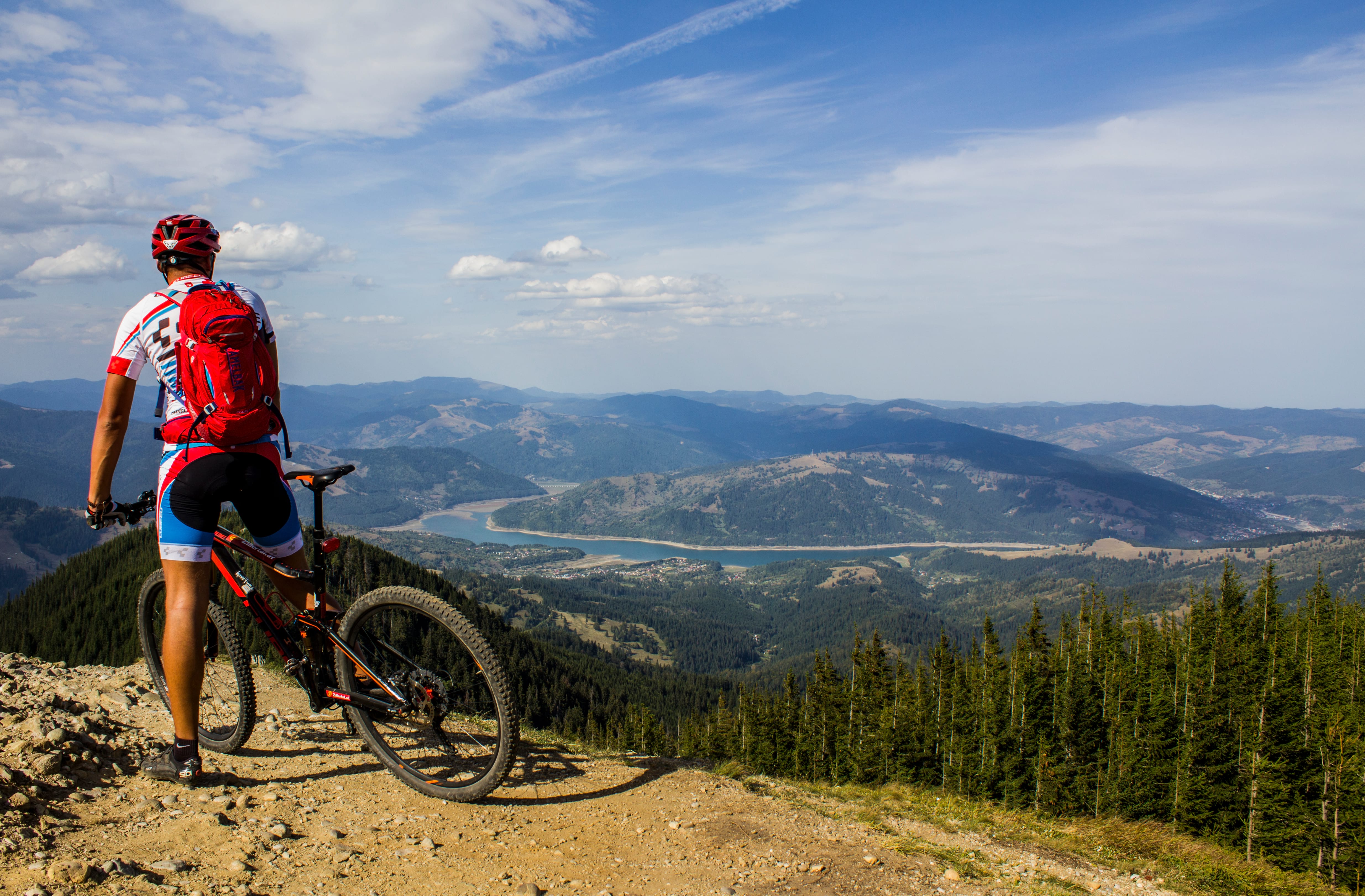 beautiful panorama of mountains and a lake with a biker in the center