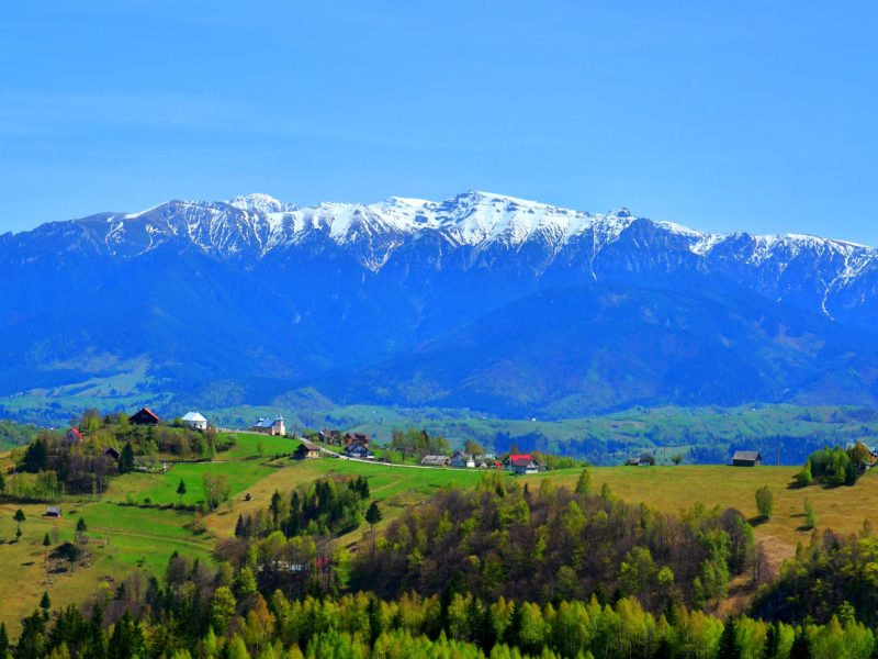 picturesque village of Magura with a snowy ridge in the background